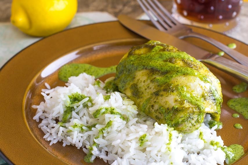 lemon lime mojo sauce on chicken thigh, plated with white rice on a brown plate