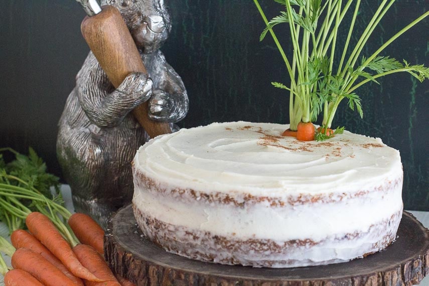 low FODMAP carrot cake with cream cheese frosting on a wooden plate with decorative bunny in the background.-2