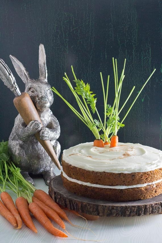 low FODMAP carrot cake with cream cheese frosting on a wooden plate with decorative bunny in the background.-3