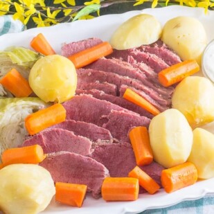 oval white platter of corned beef, cabbage, potatoes and carrots