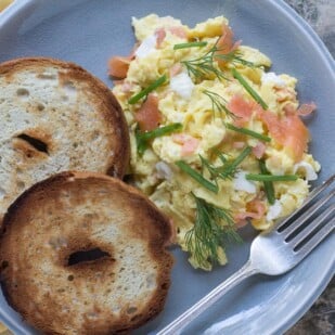 scrambled eggs with smoked salmon, cream cheese, chives nad dill on a crackled plate with toasted bagels-2