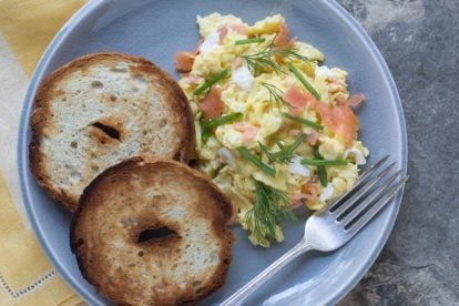 scrambled eggs with smoked salmon, cream cheese, chives nad dill on a crackled plate with toasted bagels-2