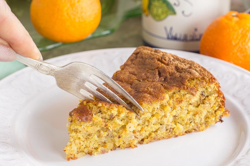 slice of clementine almond cake on a white plate; fork cutting into it