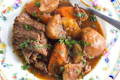 slow cooker pot roast, plated on a decorative floral plate