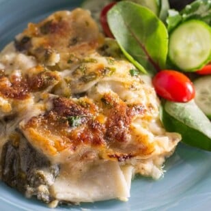 Chicken & Spinach Lasagna Bake on a blue plate with salad alongside