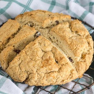 whole Irish soda bread on round cooling rack with green and white kitchen cloth