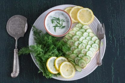 Poached salmon with cucumber scales and creamy yogurt dill sauce on a white plate-2