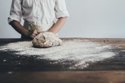 Female baker working with heavily floured dough on a wooden surface