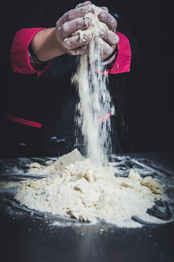 Baker working with flour against a dark background; Choosing a Low FODMAP All-Purpose Flour