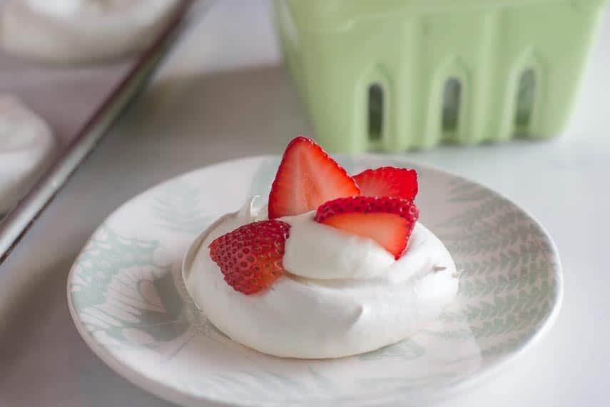 meringue nests with whipped cream on a green and white plate