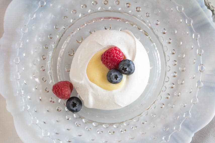 overhead view meringue nests with lemon curd on a glass plate