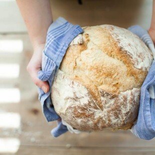 sourdough bread held in hands with a blue kitchen towel