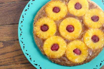 pineapple upside down cake with raspberries on a teal plate