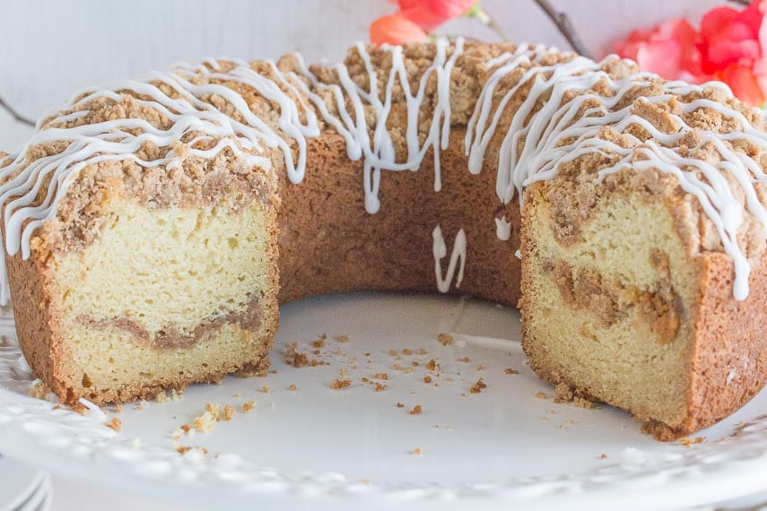 cinnamon streusel coffee cake in a ring shape, cut open to show inside, on a white platter