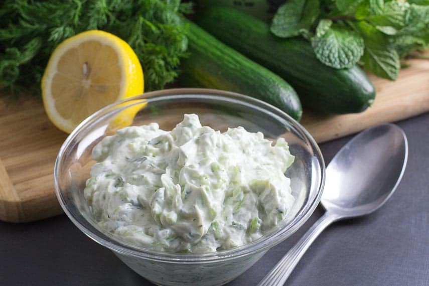 tzatziki in a glass bowl and ingredients in background