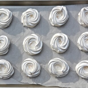 piped meringue nests on parchment paper