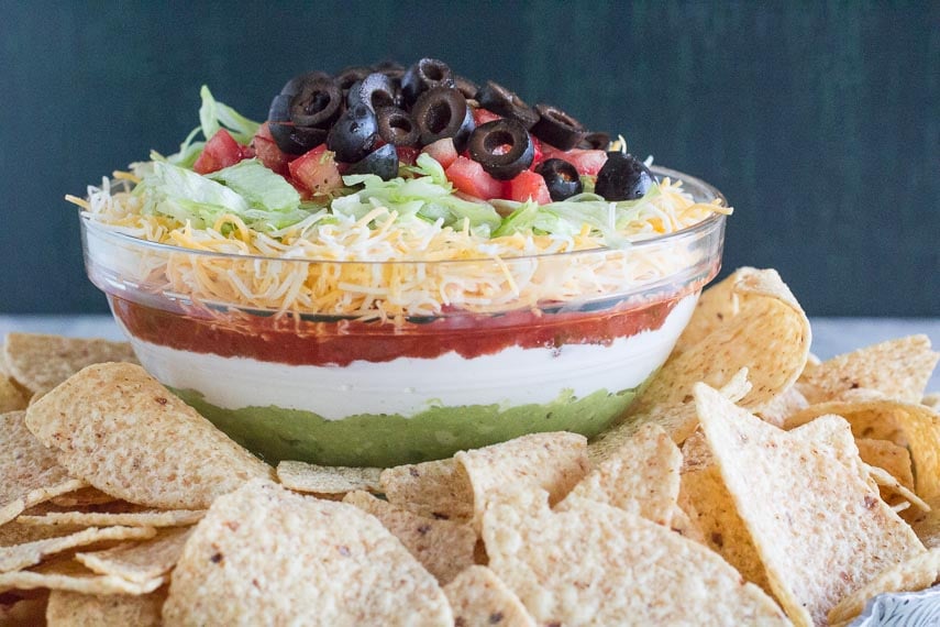 7-layer dip in glass bowl with corn chips in foreground