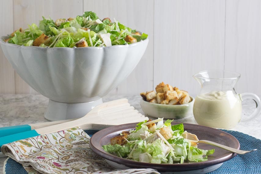 Chopped chicken Caesar salad on brown plate and blue placemat