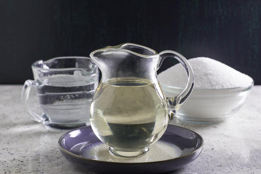 Simple Syrup in clear glass pitcher on blue ceramic dish