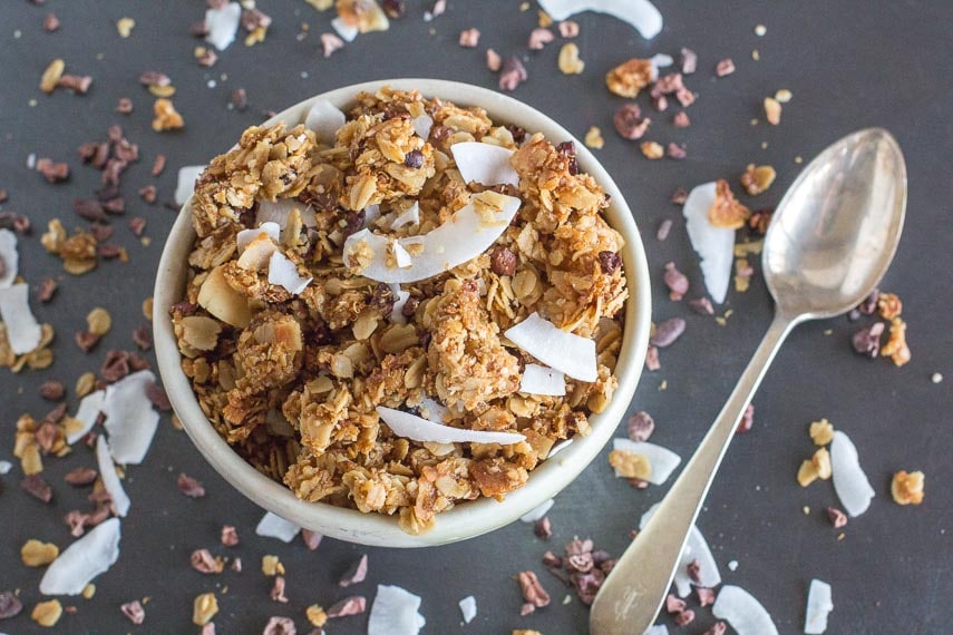chocolate coconut granola closeup in white bowl with spoon alongside