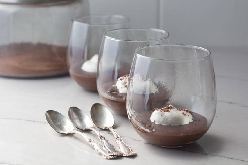 chocolate almond milk pudding in glasses aith silver spoons alongside