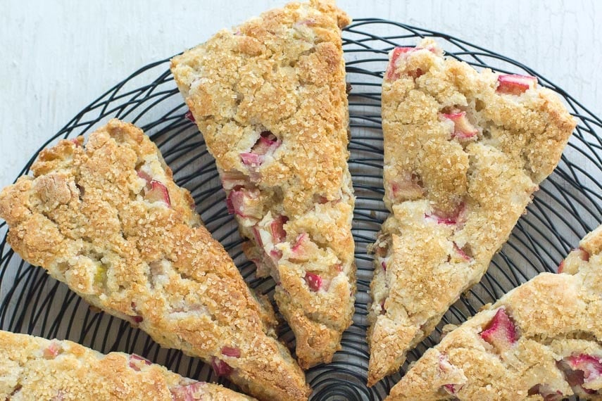 closeup of rhubarb scones on a black wire rack on white wood background