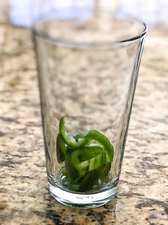 jalapeno ready for muddling in a clear glass on granite counter; Not a Paloma cocktail