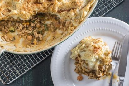 verhead image of turkey shepherd's pie; oval casserole dish and an individual serving on a white plate with fork and knife