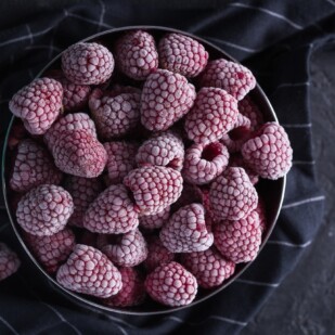frozen raspberries in a dark bowl. Fresh vs. Frozen Fruits & Vegetables