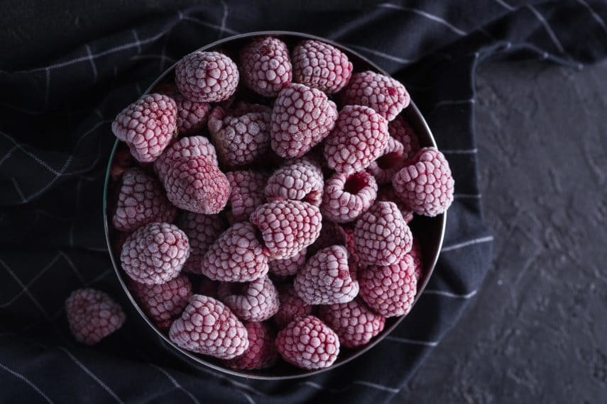 frozen raspberries in a dark bowl. Fresh vs. Frozen Fruits & Vegetables