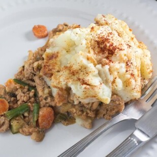 serving of turkey shepherd's pie on white plate with fork and knife