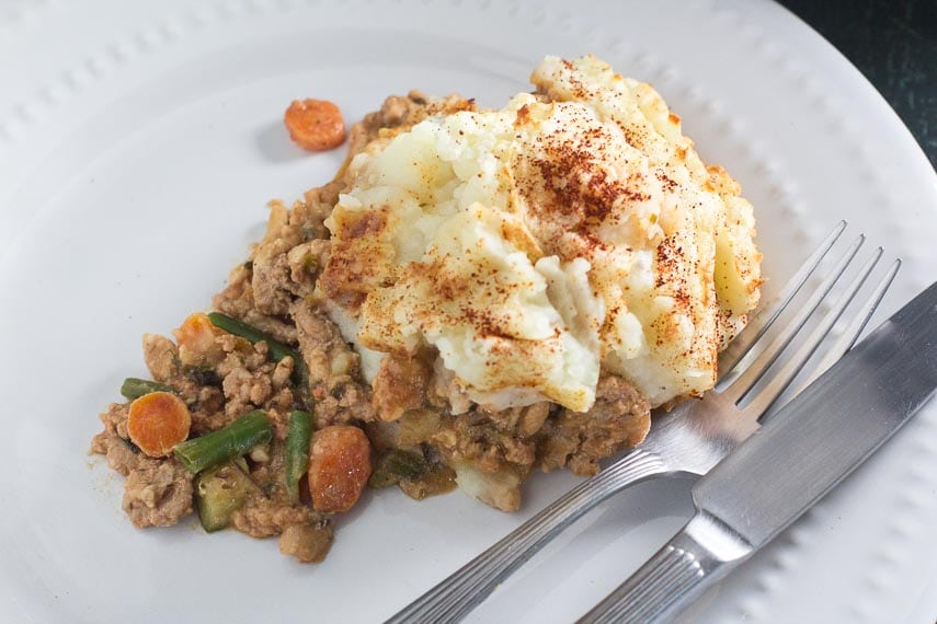 serving of turkey shepherd's pie on white plate with fork and knife