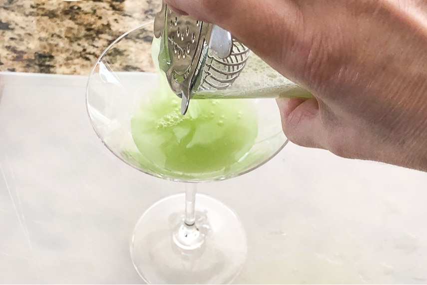 straining our Cucumber Wasabi Gimlet into a martini glass