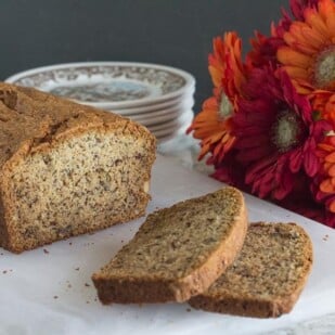 FODMAP IT banana bread closeup on white cutting board with Gerbera daisies in background