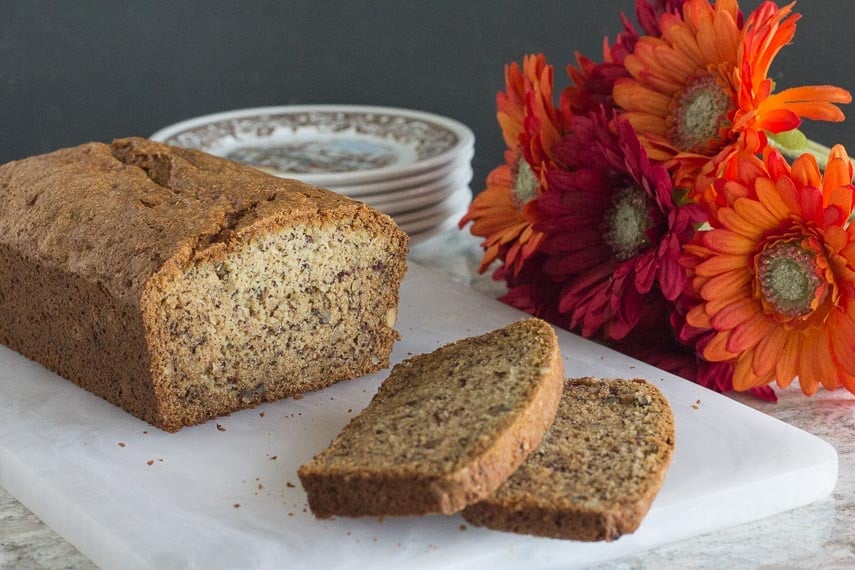 FODMAP IT banana bread closeup on white cutting board with Gerbera daisies in background