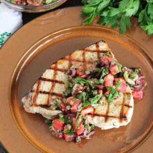 Grilled Swordfish with Tomato Olive Salsa on a brown plate