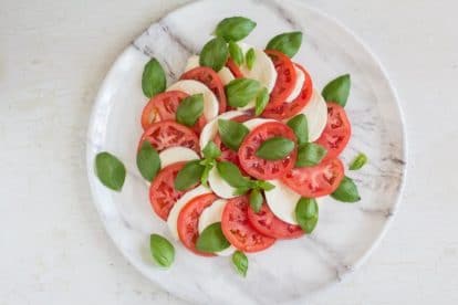 caprese salad on marble dish on white wooden board