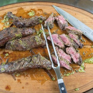carving grilled hanger steak with Charmoula sauce on cutting board with Viking carving set
