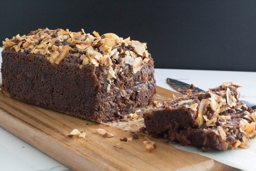 chocolate coconut banana bread on a wooden cutting board, with slices and knife alongside