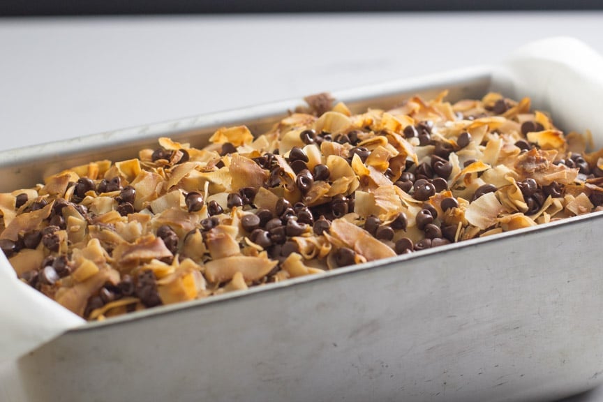 chocolate coconut banana bread in pan showing off its decadent coconut chocolate topping