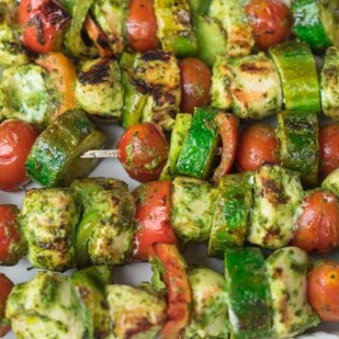 closeup of grilled chicken and vegetable kebobs on a white platter