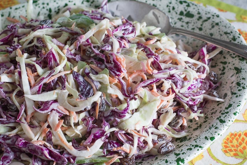 creamy coleslaw with raisins on a green and white splattered platter