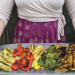 low FODMAP Grilled vegetables on a large platter, held by a woman in a dress