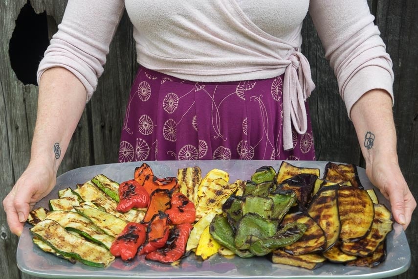 low FODMAP Grilled vegetables on a large platter, held by a woman in a dress