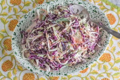 overhead of creamy coleslaw with raisins on a green and white splattered platter