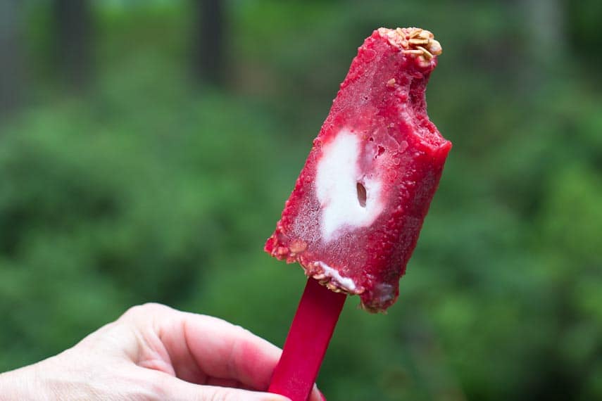 bite out of a strawberry yogurt granola popsicle held in hand