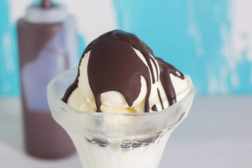 Chocolate Shell on vanilla ice cream in a clear glass dish; chocolate shell in squirt bottle in background