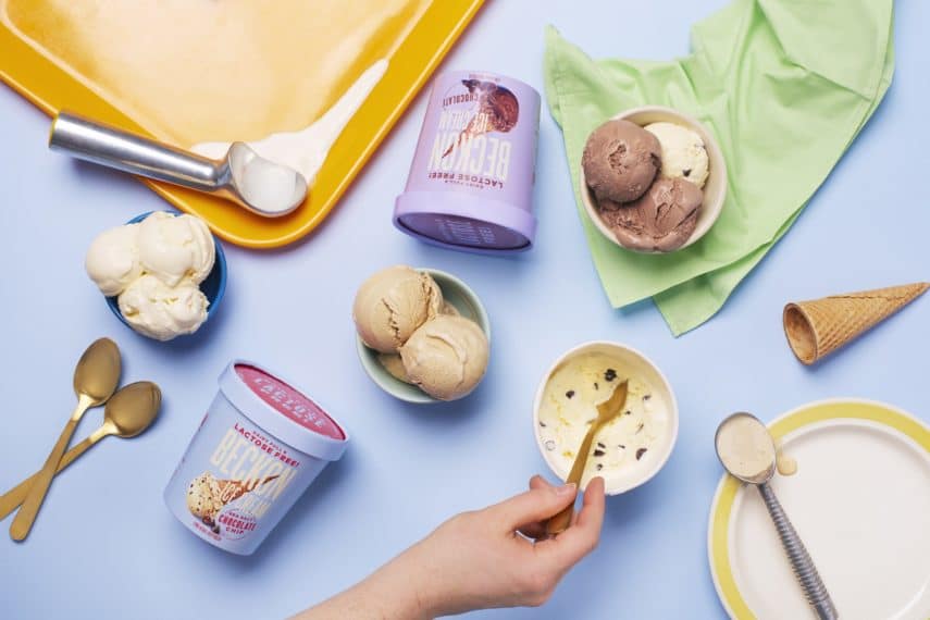 Pale blue background with two ice cream containers laying flat, three bowls of ice cream, and a yellow tray with melting ice cream