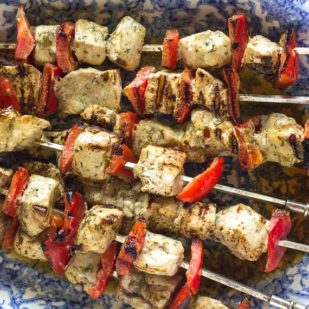 closeup of swordfish kebobs on an oval blue and white platter