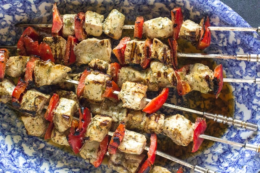 closeup of swordfish & bell pepper kebobs on an oval blue and white platter